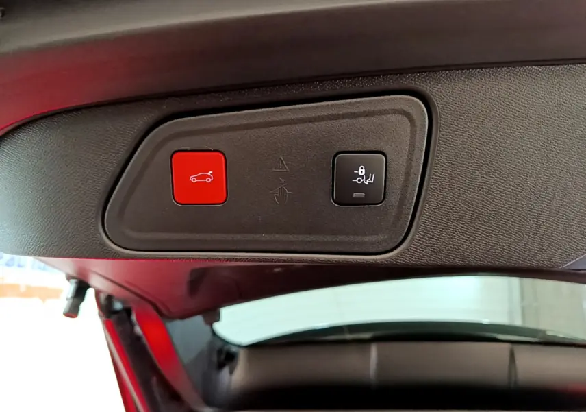 Gros plan sur les boutons de fermeture électrique du coffre et de rabattement des sièges dans un Peugeot 3008 gris clair.