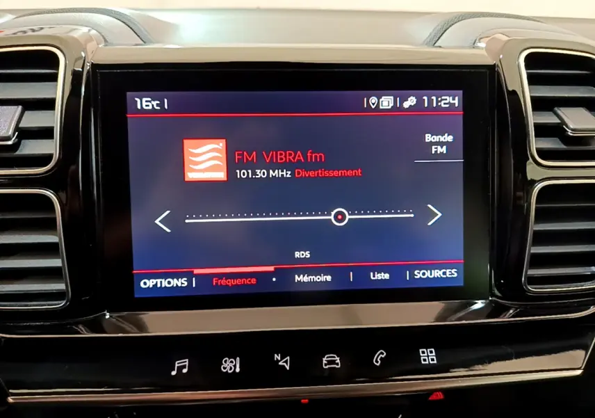 Écran tactile central affichant la radio FM dans l'habitacle noir du Citroën C5 Aircross, vue frontale rapprochée.