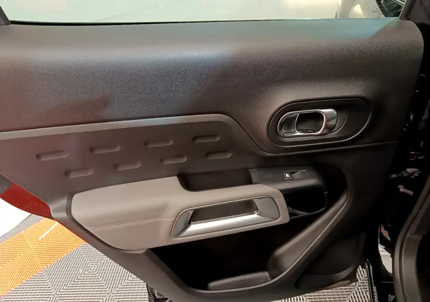 Gros plan sur la porte intérieure côté gauche du Citroën C5 Aircross noir, avec poignée argentée et garniture bicolore.