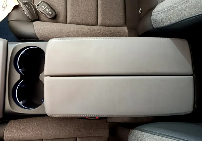 Vue plongeante sur l'accoudoir central gris et les sièges tissu marron du Citroën C5 Aircross 2020 noir.