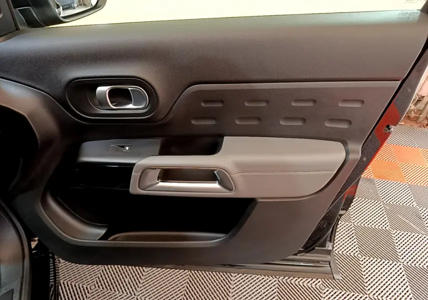 Vue rapprochée de la porte intérieure côté gauche du Citroën C5 Aircross noir, avec poignée argentée et garniture grise.