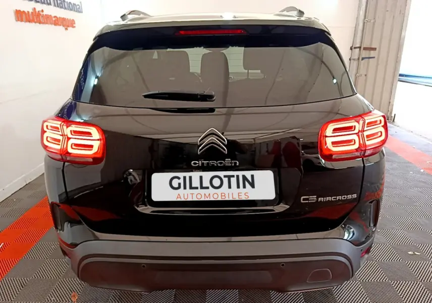 Vue arrière du Citroën C5 Aircross noir avec feux arrière LED distinctifs allumés en intérieur showroom.