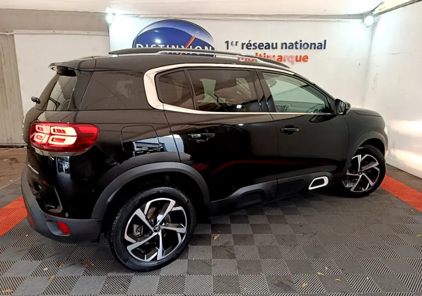 Vue 3/4 arrière droite d'un Citroën C5 Aircross noir avec jantes alliage et feux arrière LED allumés.