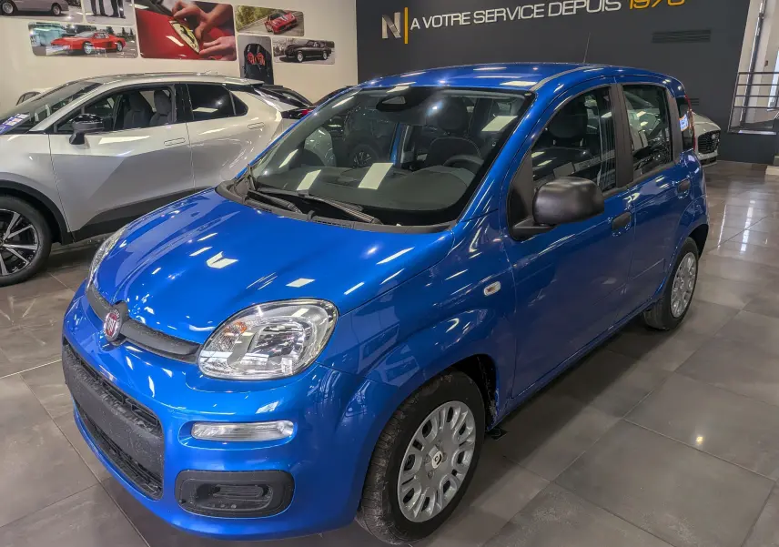 Vue 3/4 avant droite d'une FIAT Panda 1.0 Hybrid 2025 en Bleu Italia, compacte avec rétroviseurs noirs et jantes acier.