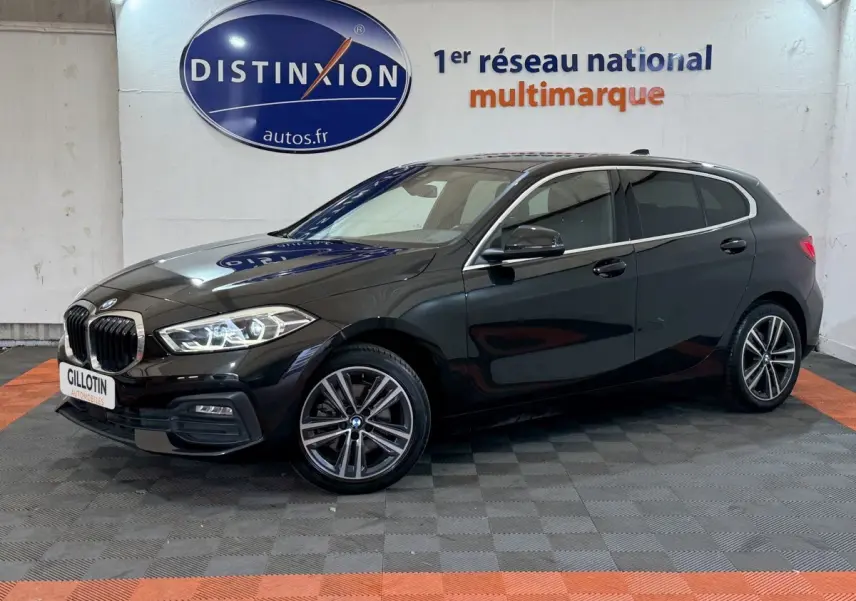 BMW Série 1 116d Business Design noire vue de profil droit en intérieur avec jantes alliage et phares LED allumés.