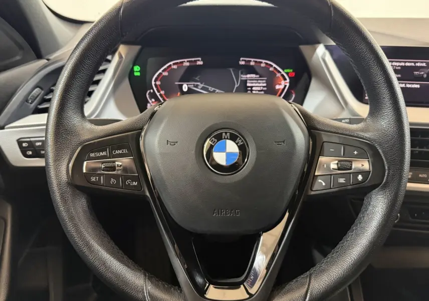 Vue rapprochée du volant cuir noir BMW Série 1 116d 2022 avec commandes multifonctions et tableau de bord digital.