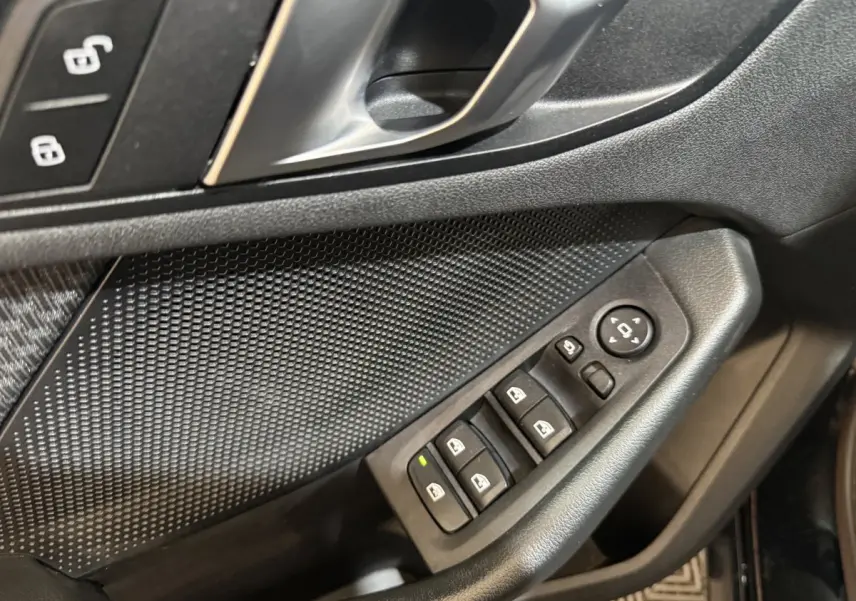 Gros plan sur la porte côté conducteur de la BMW Série 1 noire, avec commandes électriques des vitres et rétroviseurs.