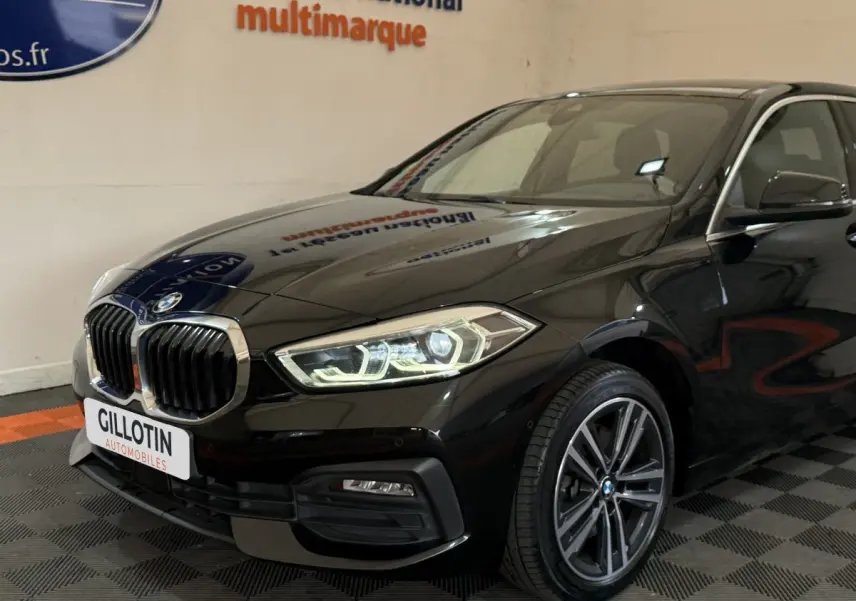 BMW Série 1 116d Business Design noire vue en 3/4 avant droit, avec phares LED et calandre chromée distinctive.