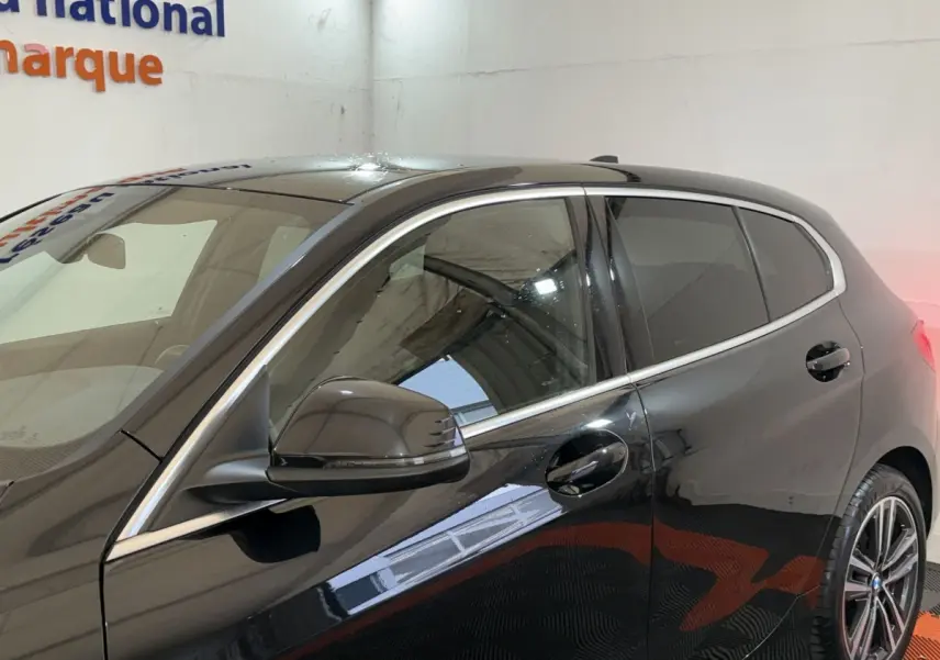 Vue latérale gauche rapprochée d’une BMW Série 1 116d noire mettant en valeur les contours chromés et la jante alliage.