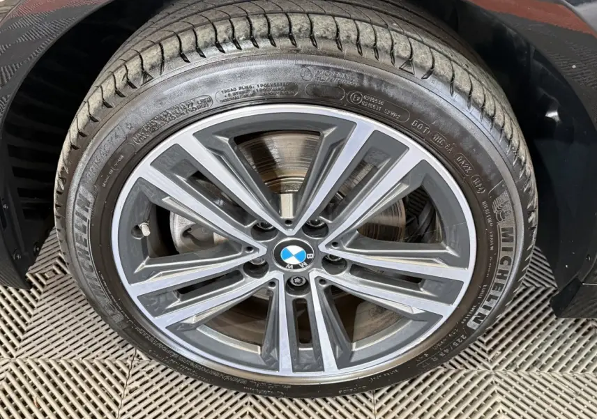 Gros plan sur la jante alliage grise et noire d’une BMW Série 1 116d, avec pneu Michelin visible.