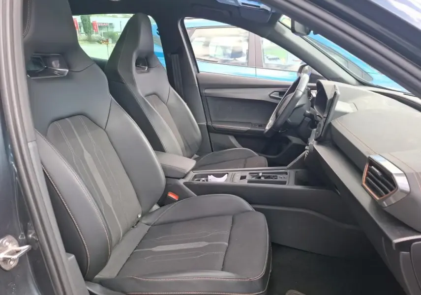 Vue intérieure côté gauche de la CUPRA Formentor 1.4 E-HYBRID 245 VZ 2024, sièges noirs en tissu avec surpiqûres contrastées.
