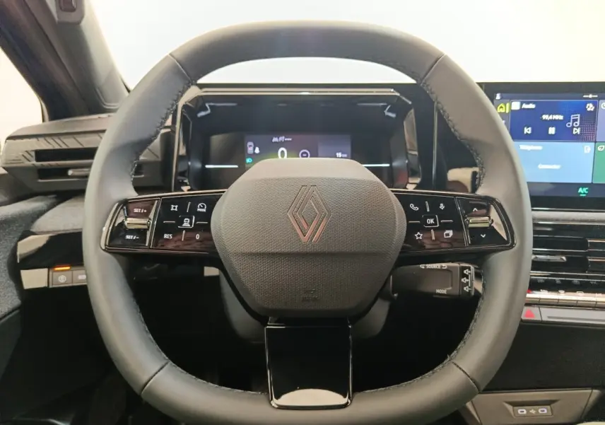 Vue rapprochée du volant multifonctions noir de la Renault Clio 2026 avec tableau de bord digital et écran central.