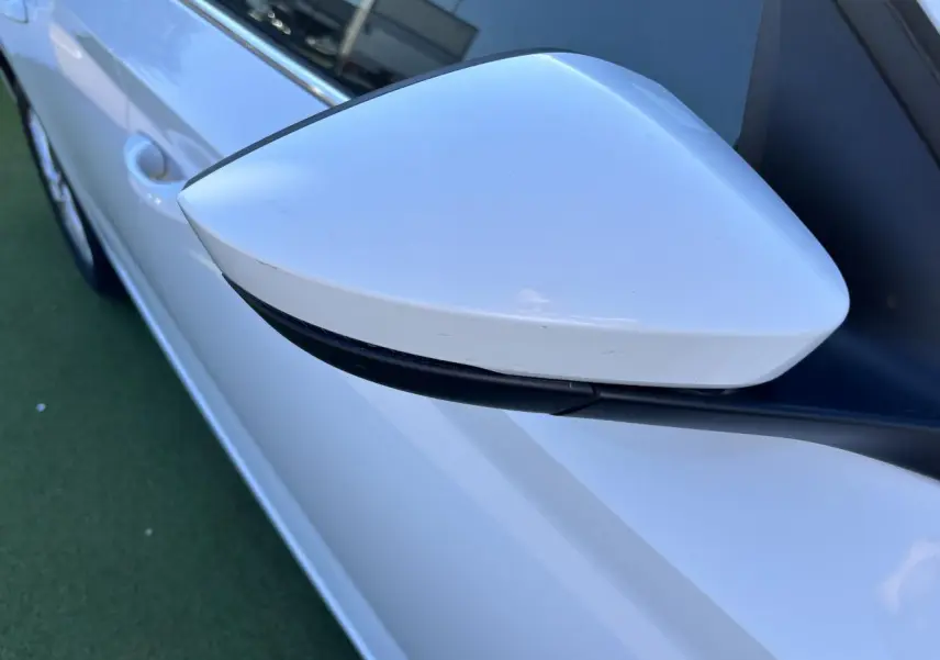 Rétroviseur blanc glacier côté gauche de la Skoda Scala 2024, avec carrosserie et poignée de porte visibles.