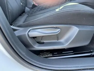 Gros plan sur la manette de réglage manuel du siège conducteur noir de la Skoda Scala blanc glacier 2024 côté gauche.