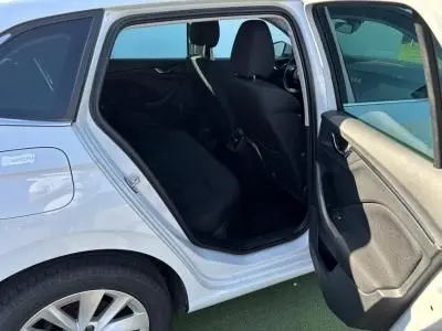 Vue côté gauche arrière d'une Skoda Scala blanc glacier avec porte ouverte dévoilant l'intérieur noir des sièges arrière.
