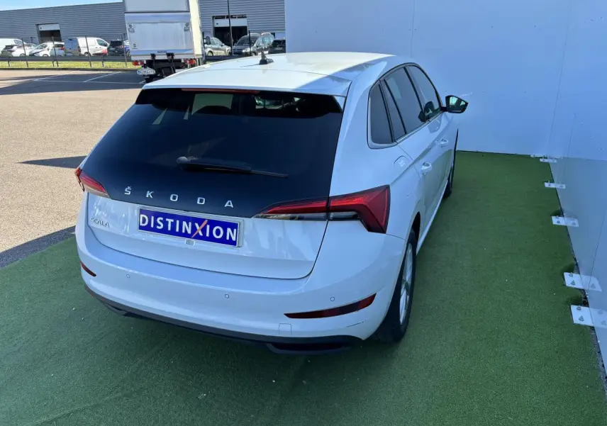 Vue 3/4 arrière droite d'une Skoda Scala blanche glacier avec feux arrière LED et vitres teintées.