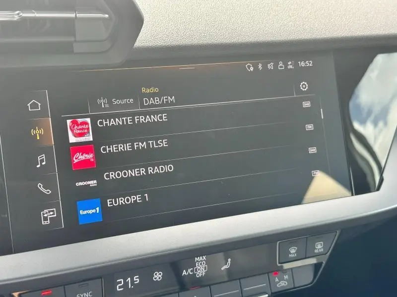 Écran tactile multimédia affichant les stations radio dans l'Audi A3 Sportback 30 TFSI blanc Arkona, vue intérieure centrale.