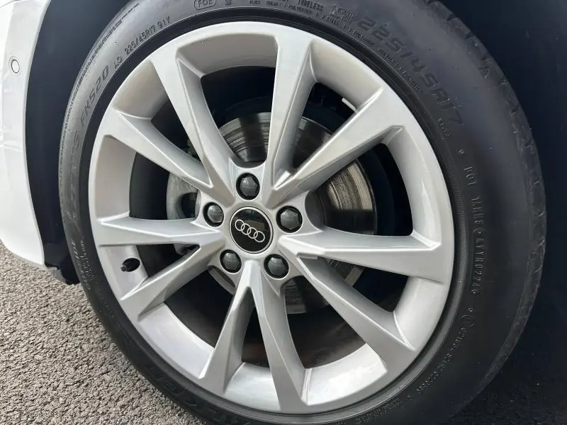 Gros plan sur la jante alu argentée de l'Audi A3 Sportback blanc Arkona, mettant en valeur le logo Audi central.