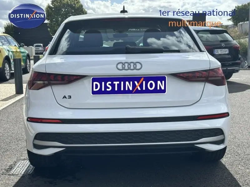 Vue arrière d'une Audi A3 Sportback blanche Arkona avec feux arrière allongés et logo Audi visible.