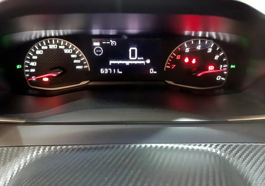 Tableau de bord numérique du Peugeot 2008 gris clair, affichant compteur vitesse et compte-tours éclairés.