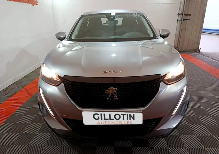 Peugeot 2008 gris clair vue de face avec phares allumés et calandre noire distinctive.