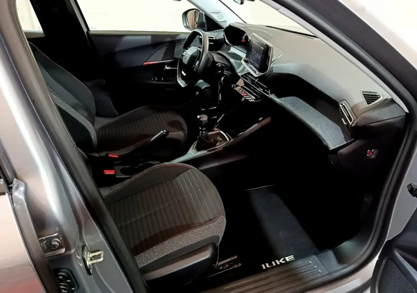 Intérieur côté conducteur du Peugeot 2008 gris clair 2022, avec tableau de bord moderne et écran tactile central.