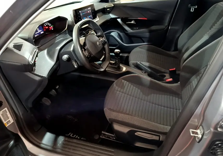 Intérieur avant droit du Peugeot 2008 gris clair 2022, volant cuir, tableau de bord numérique et écran tactile visible.