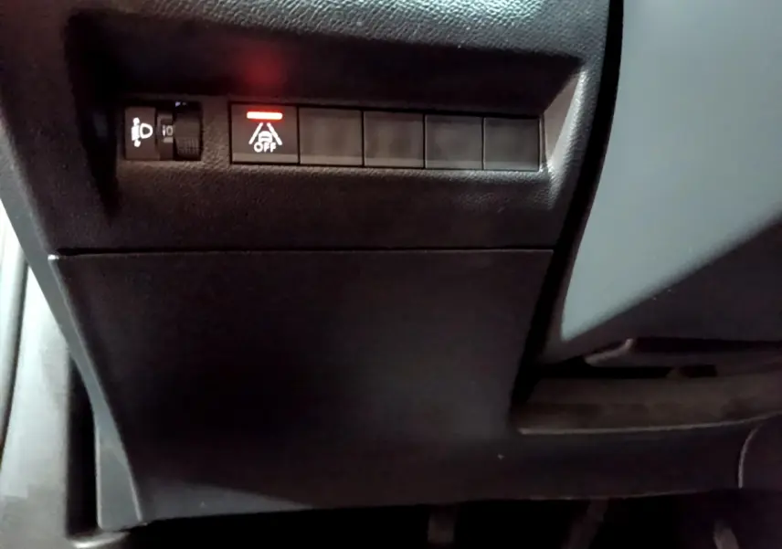 Vue rapprochée du tableau de bord côté conducteur du Peugeot 2008 gris clair, avec bouton d'assistance désactivée allumé.