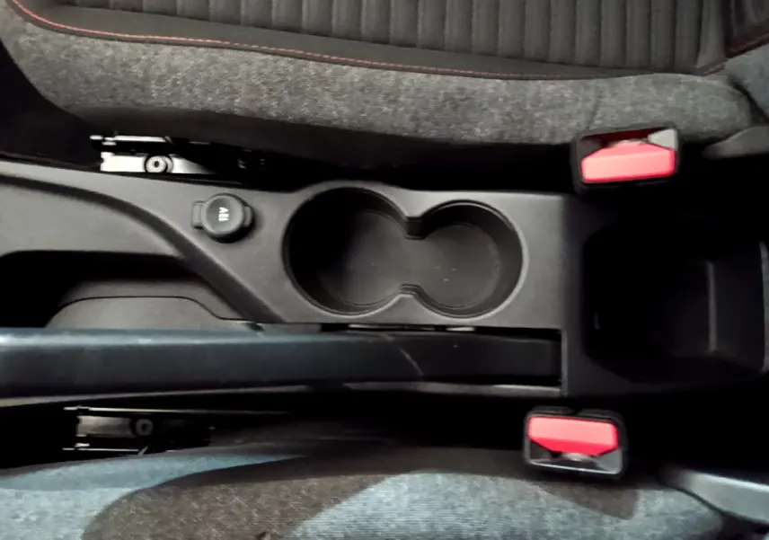 Gros plan sur la console centrale de la Peugeot 2008 gris clair, avec porte-gobelets et ceintures rouges visibles entre les sièges.