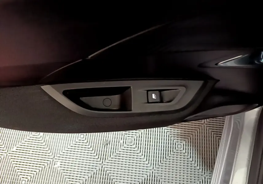 Gros plan sur la poignée intérieure et bouton de verrouillage de la porte côté conducteur d’un Peugeot 2008 gris clair 2022.