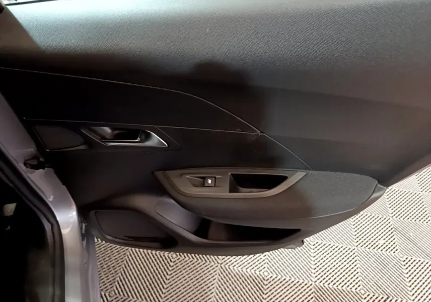 Gros plan sur la porte côté gauche gris clair du Peugeot 2008 2022 avec commande de lève-vitre et poignée intégrée.