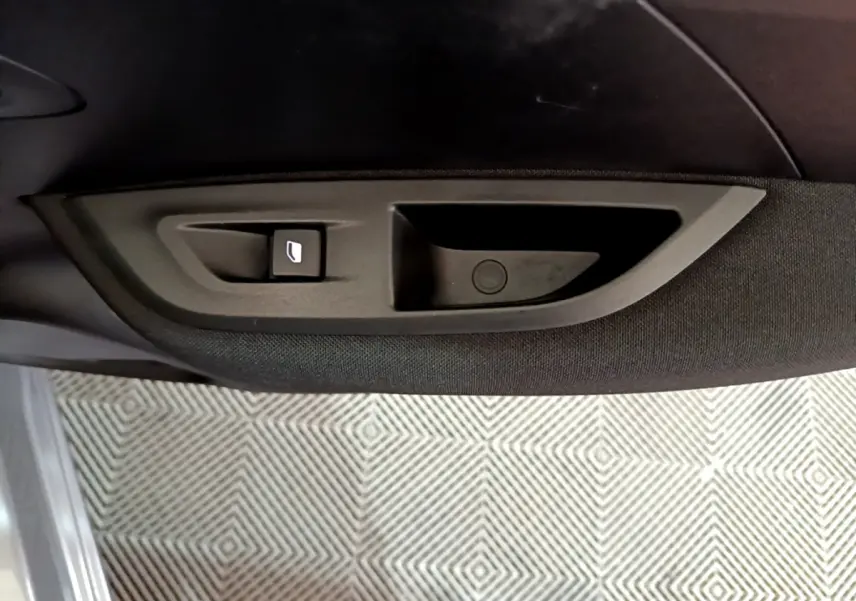 Détail de la poignée intérieure et bouton de lève-vitre côté gauche d’un Peugeot 2008 gris clair 2022.