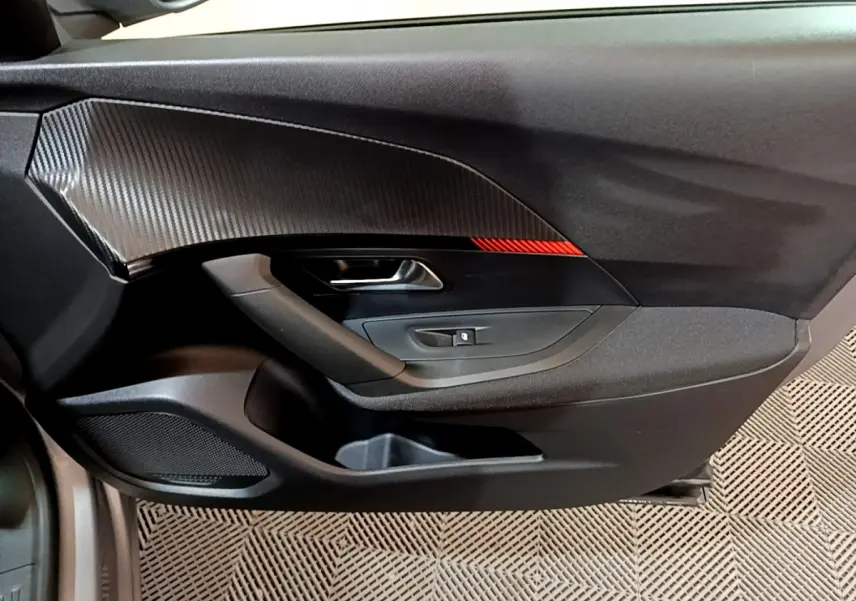 Gros plan sur la porte côté conducteur du Peugeot 2008 gris clair, avec insert décoratif noir et rouge.