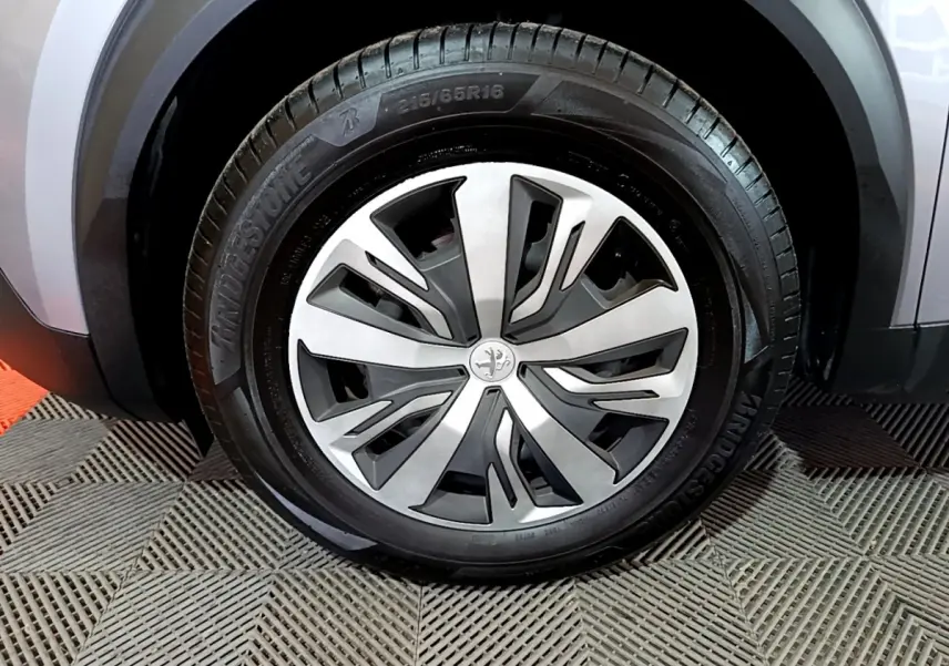 Gros plan sur la roue avant droite d’un Peugeot 2008 gris clair, avec jante alliage au design moderne.