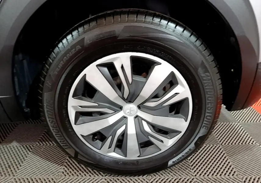 Gros plan sur la roue avant droite du Peugeot 2008 gris clair, mettant en valeur la jante moderne et le pneu Bridgestone.