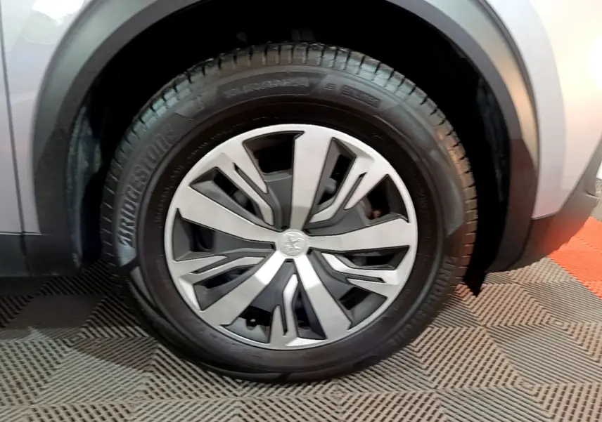 Gros plan sur la roue avant gauche du Peugeot 2008 gris clair, mettant en valeur la jante moderne et le pneu Bridgestone.