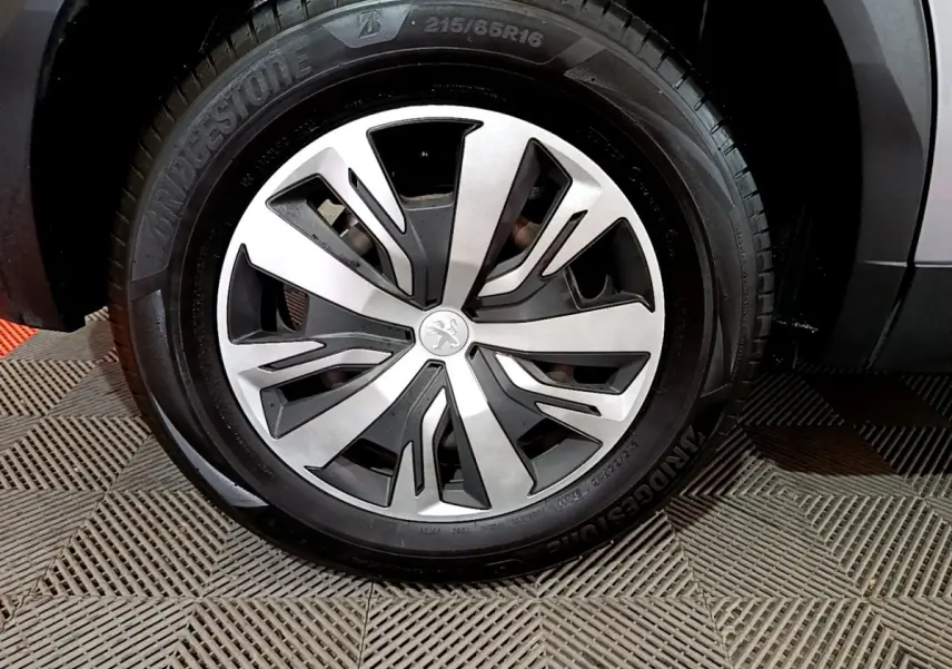 Gros plan sur la roue avant droite d’un Peugeot 2008 gris clair, avec jante alliage et pneu Bridgestone.