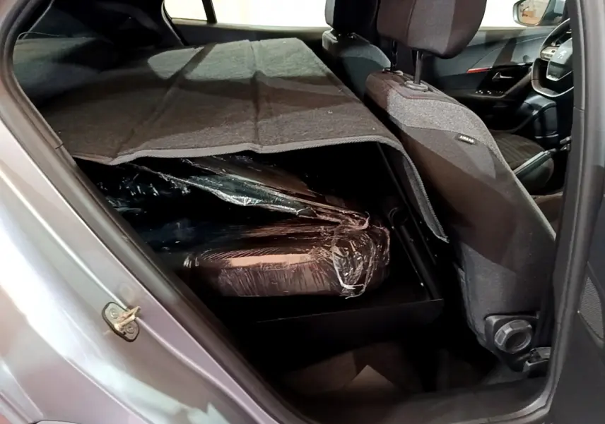 Vue intérieure côté gauche du Peugeot 2008 gris clair 2022, sièges arrière rabattus avec chargement protégé par une couverture.