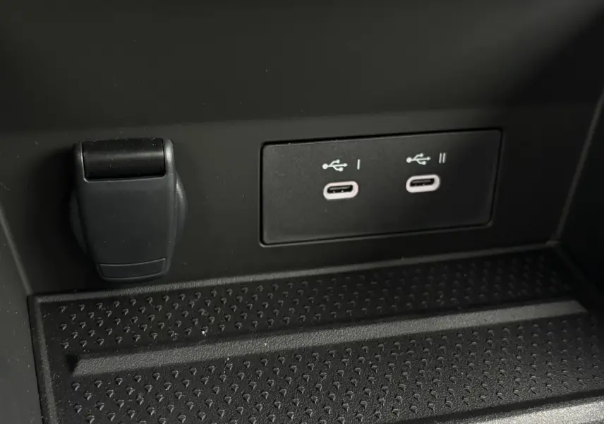 Gros plan sur deux ports USB-C et une prise 12V noirs dans le compartiment avant d'un Renault Captur gris.