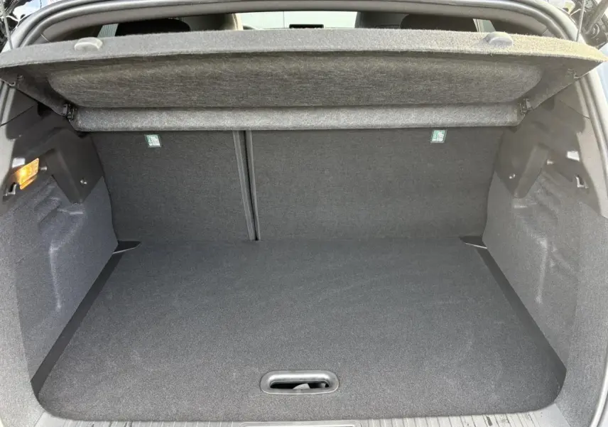 Coffre ouvert vu de l’arrière du Renault Captur gris Rafale, intérieur noir avec cache-bagages déployé.