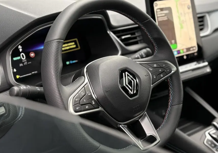 Gros plan sur le volant noir avec surpiqûres tricolores et tableau de bord numérique du Renault Captur Esprit Alpine 2025.