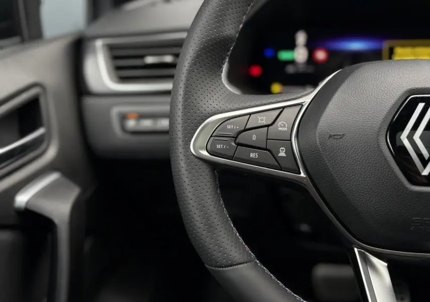 Gros plan sur le volant perforé avec surpiqûres tricolores et commandes multifonctions du Renault Captur Esprit Alpine 2025.