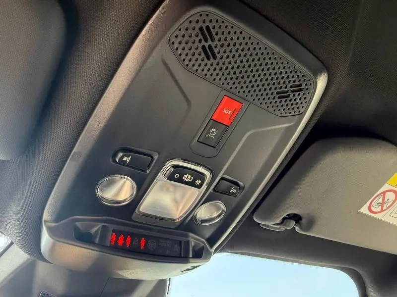 Vue en contre-plongée du plafonnier intérieur noir du Peugeot 2008 rouge Elixir avec boutons SOS et éclairage.