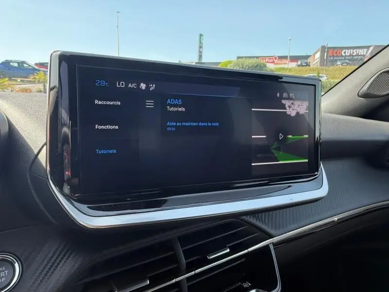Écran tactile central du tableau de bord du Peugeot 2008 2025, affichant les tutoriels ADAS, intérieur noir moderne.