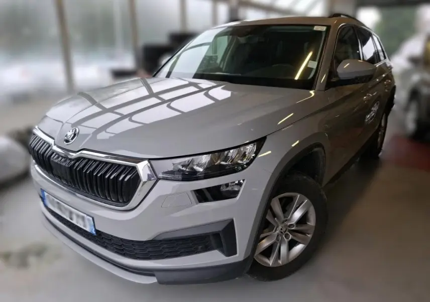 Vue 3/4 avant droit d'un Skoda Kodiaq gris clair 2023, mettant en valeur sa calandre distinctive et ses phares modernes.