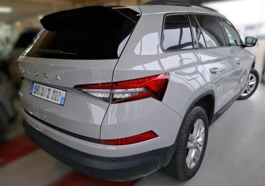 Vue 3/4 arrière droite d’un Skoda Kodiaq gris clair 2023 avec feux arrière LED et toit noir brillant.