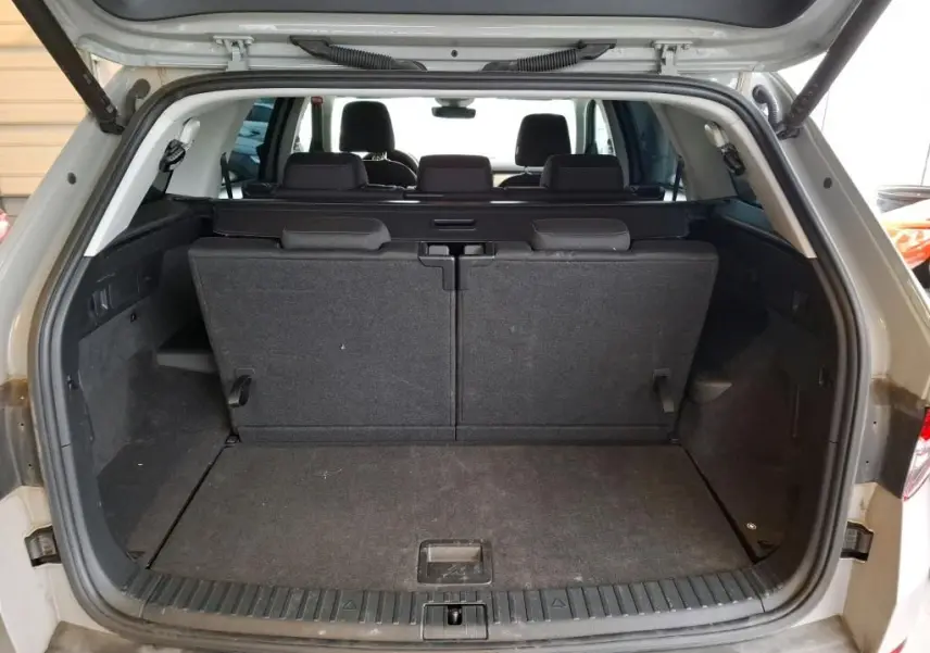 Vue arrière du coffre ouvert d'un Skoda Kodiaq gris clair 2023, montrant la troisième rangée de sièges relevée.