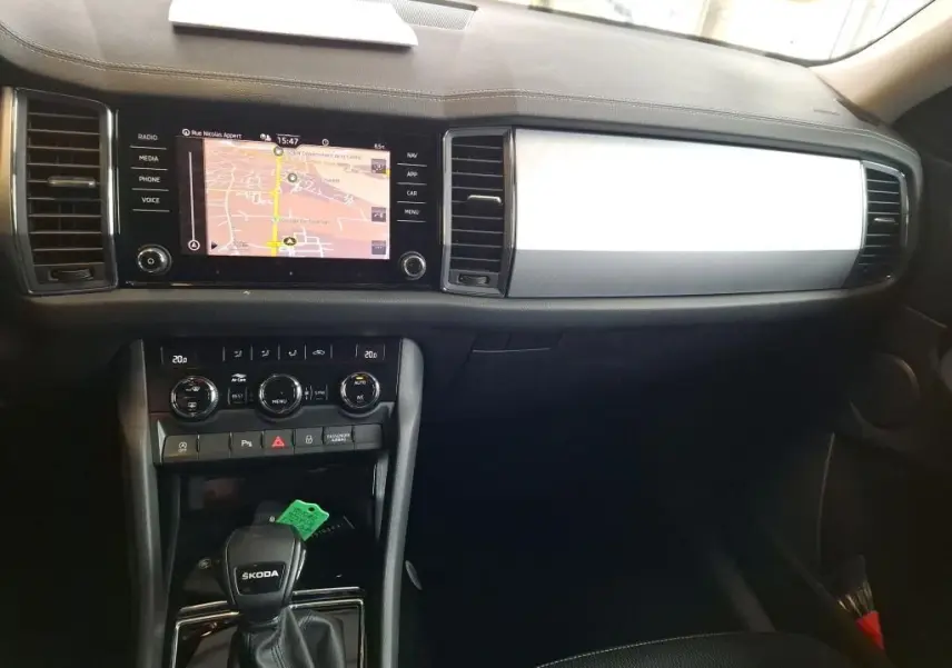 Vue intérieure du tableau de bord et console centrale du Skoda Kodiaq gris clair, avec écran tactile et commandes climatisation visibles.