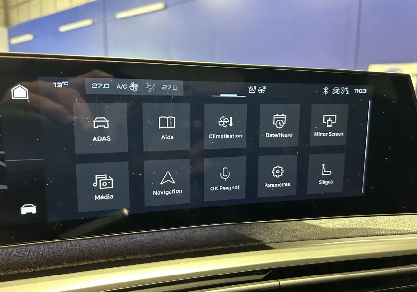 Écran tactile central du tableau de bord du Peugeot 3008 Hybrid 2026 affichant les menus de climatisation, navigation et aides à la conduite.