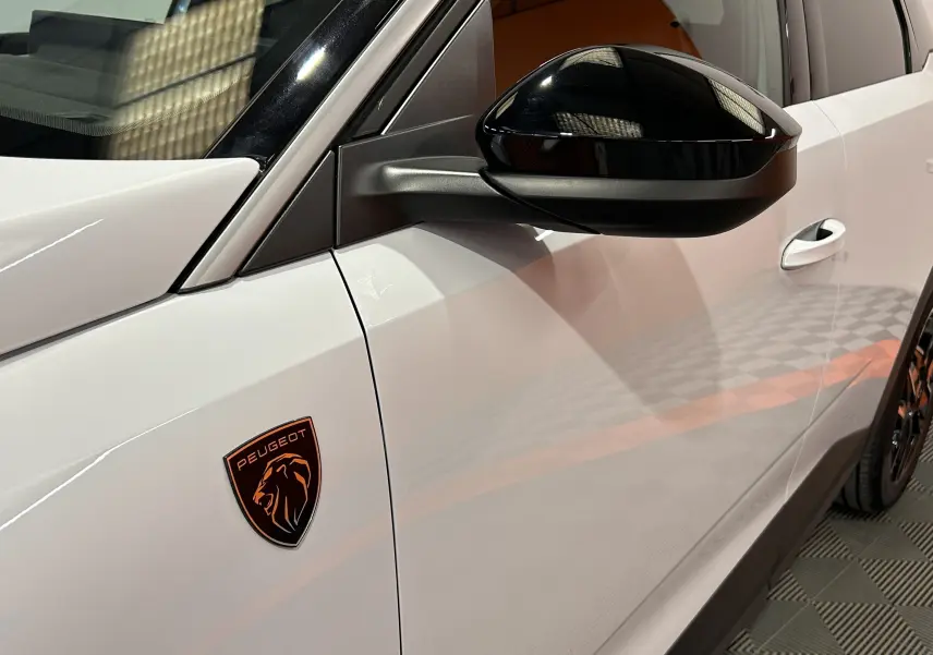 Détail côté gauche d’un Peugeot 3008 blanc Okenite avec rétroviseur noir brillant et logo Peugeot orange.